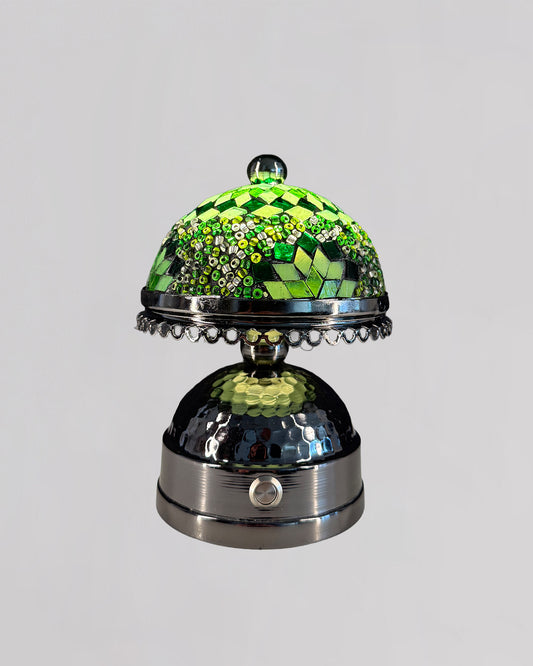 Decorative glass object with green and silver design on a gray background
