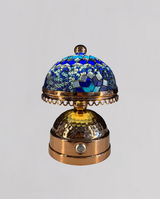 Decorative object with blue mosaic top and gold base on a light gray background