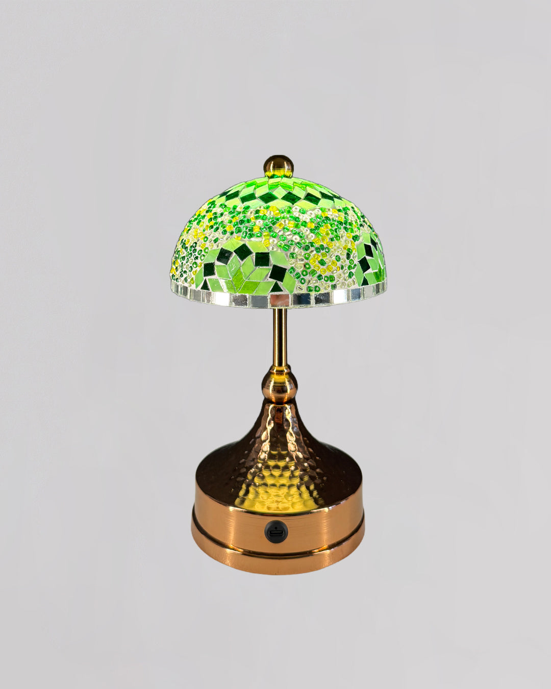 Decorative table lamp with a green mosaic shade on a gray background