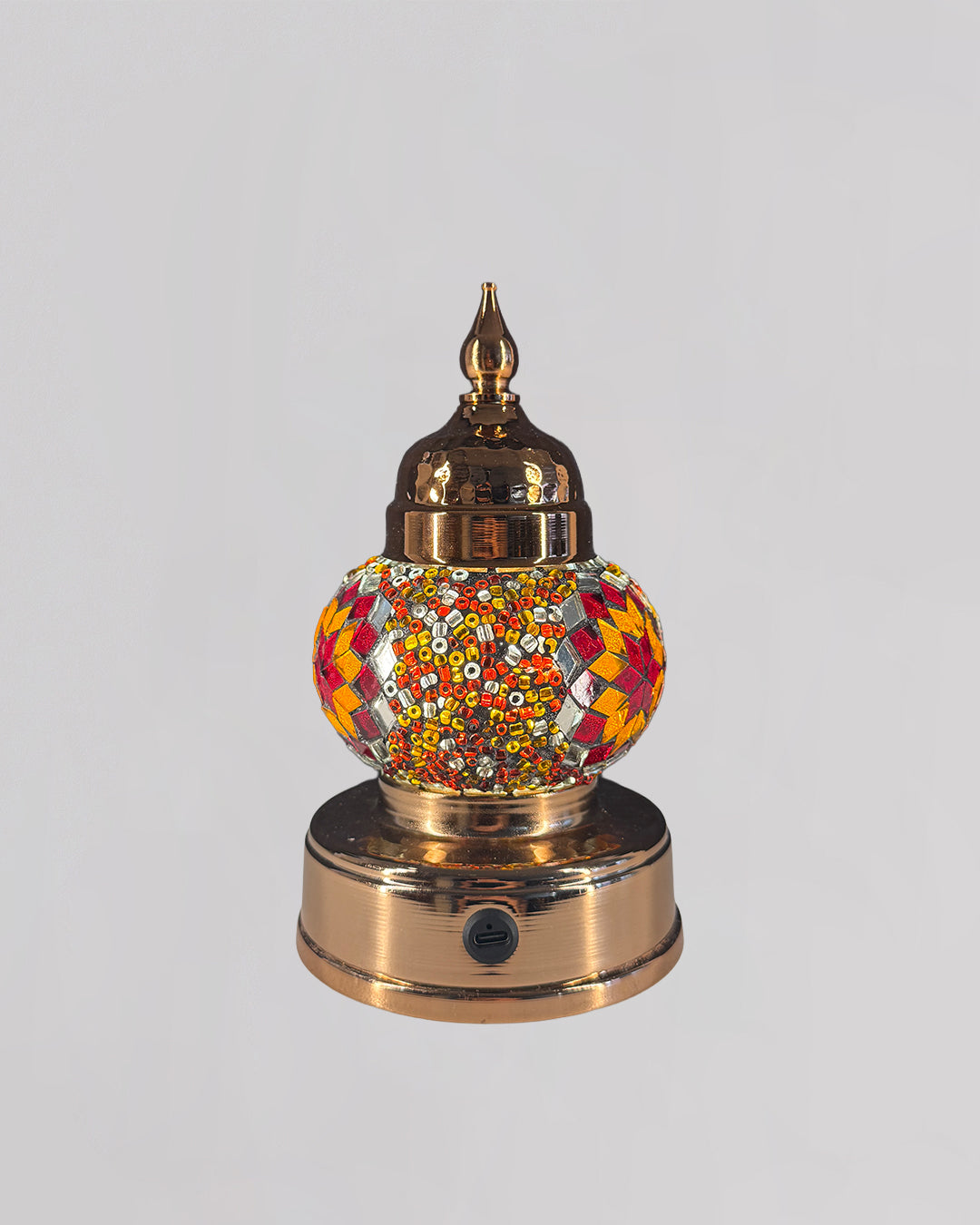 Decorative mosaic lamp with orange and red glass creating rich and warm light.