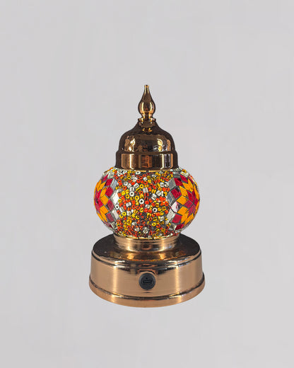Decorative mosaic lamp with orange and red glass creating rich and warm light.